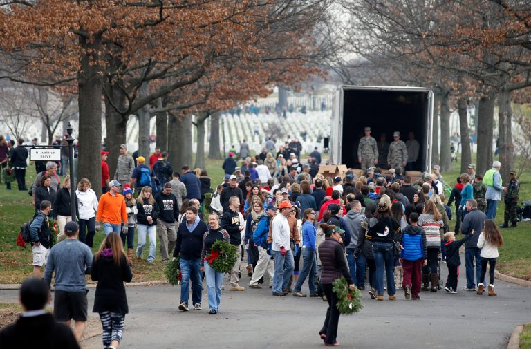 A crowd of volunteers gathers around a truck to get wreaths to place at graves as part of Wreaths Across America at Arlington National Cemetery. (AP Photo/Alex Brandon)