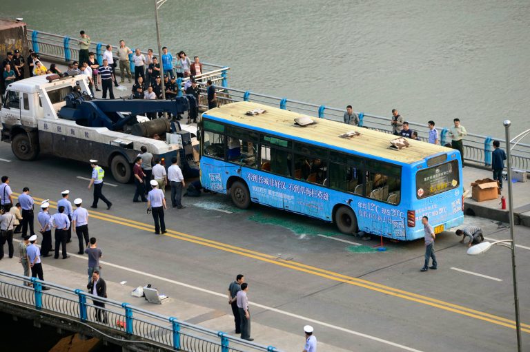 In this photo released by China's Xinhua News Agency taken on Monday, May 12, 2014 police personnel and others stand near a burned bus as it is prepared to be towed following an explosion in Yibin, southwest China's Sichuan Province. Authorities in southwest China said Tuesday, May 13, 2014, that police suspect that a man who died in the explosion on the bus was responsible for igniting the fire that also injured dozens. (AP Photo/Xinhua, Jiang Hongjing) NO SALES