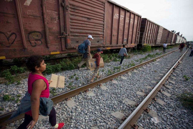 In this July 12, 2014, photo, migrants walk along the rail tracks after getting off a train during their journey toward the U.S.-Mexico border in Ixtepec, Mexico. The surge in unaccompanied minors and women with children migrating from Central America has put new attention on decades-old smuggling organizations. (AP Photo/Eduardo Verdugo)