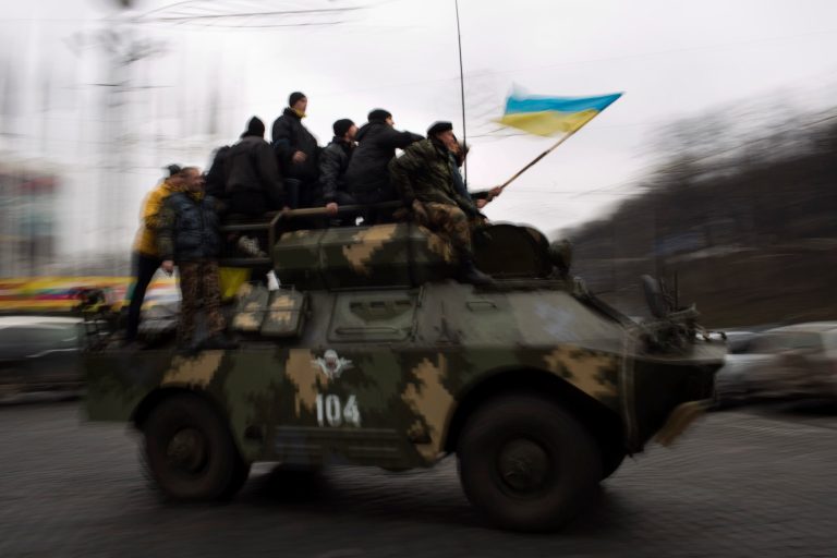 Protestors opposing Viktor Yanukovych ride on top of an army armored vehicle though a street in central Kiev, Ukraine, on Thursday. (AP Photo/Emilio Morenatti)