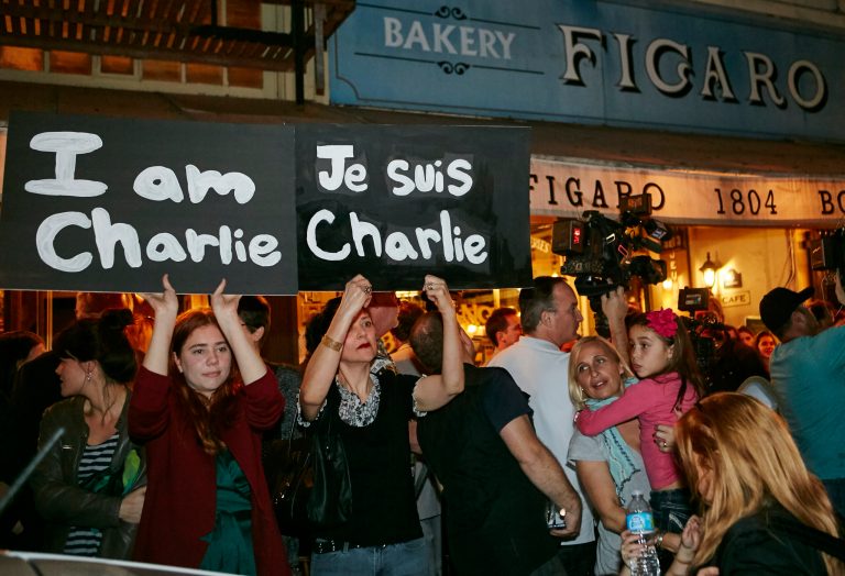 Members of the French-American community of Los Angeles hold signs reading 