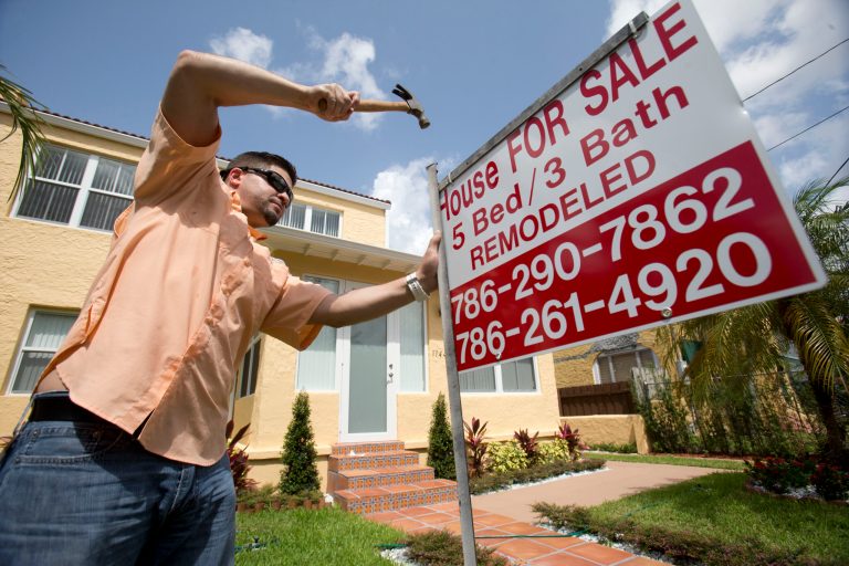 In this Friday, April 24, 2015 file photo, Robert Almirall, director of marketing and special assets coordinator for Mederos & Associates Real Estate Inc., puts up a sign in front of a home in the Shenandoah neighborhood of Miami. More Americans bought homes in May, the National Association of Realtors reported Monday, June 22, 2015, a sign of economic strength that is pushing up average prices. (AP Photo/Wilfredo Lee, File)