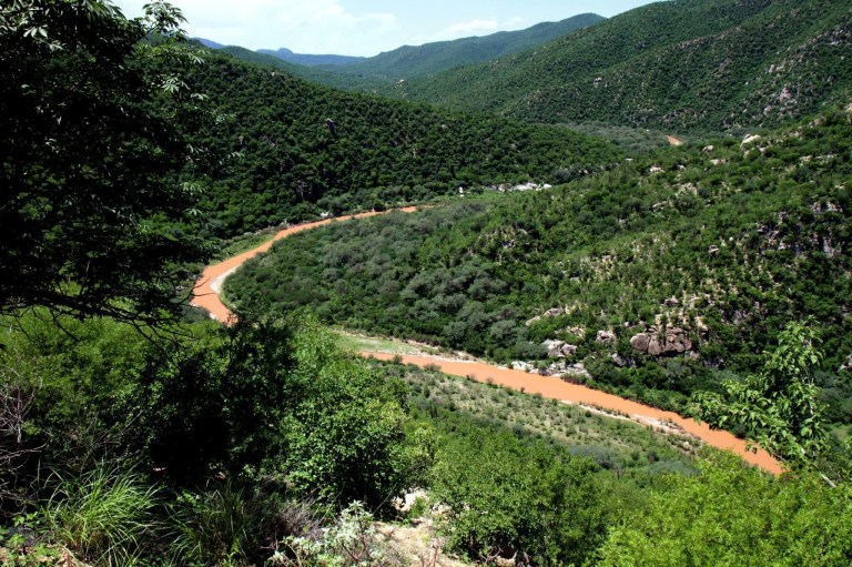 In this Aug. 12, 2014 photo, the contaminated Sonora river makes its way through the hills near the town of Mazocahui, in the northern state of Sonora, Mexico. Eighty-eight schools in Sonora state did not open Monday along with the rest of the country because of the danger of water contaminated by the spill of 10 million gallons (40,000 cubic meters) of acids from a copper mine into this and another river in the region. (AP Photo/El Imparcial, Julian Ortega)