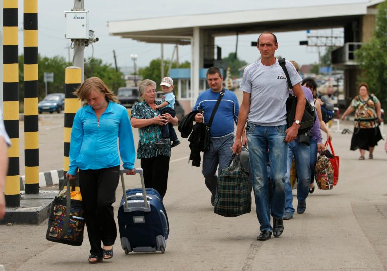 People carry their belongings as they walk to cross the border into Russia at the Ukrainian-Russian border checkpoint in Izvaryne, Luhansk region, eastern Ukraine Thursday, June 26, 2014. Thousands of Ukrainians in cars stuffed with belongings lined up Thursday at the eastern border to cross into Russia, with some saying they felt betrayed by their government and vowing never to return. (AP Photo/Dmitry Lovetsky)