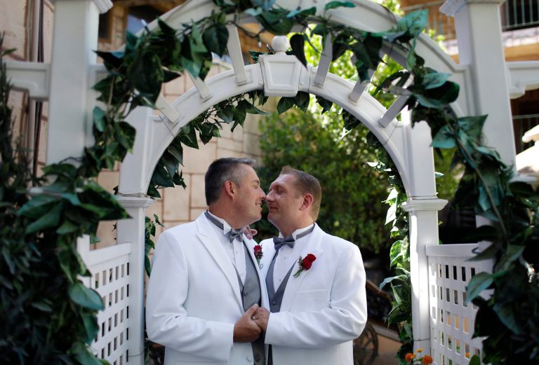In this June 30, 2014 photo, Scott McCann, left, and Jeremy Gilson of Nashua, N.H. kiss while having their commitment ceremony photos taken at the Viva Las Vegas Wedding Chapel in Las Vegas. Gay marriage isn't legal in Nevada but the Viva Las Vegas Wedding Chapel will perform a commitment ceremony for couples of any sex. (AP Photo/John Locher)