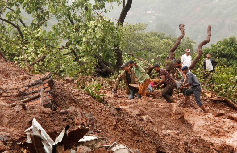 Rescue workers carry the body of a victim at the site of a landslide in Malin village, in the western Indian state of Maharashtra, Wednesday, July 30, 2014. Torrential rains triggered a massive landslide that buried a remote village in western India on Wednesday, killing more than a dozen people as it swept away scores of houses and possibly trapping many more people under debris, officials said. (AP Photo)