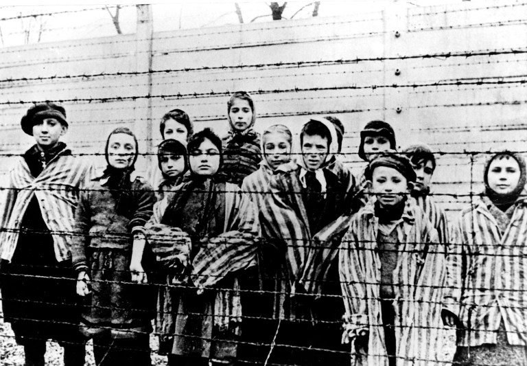 FILE - The file picture taken just after the liberation by the Soviet army in January, 1945 shows a group of children wearing concentration camp uniforms including Martha Weiss who was ten years-old, 6th from right, at the time behind barbed wire fencing in the Oswiecim (Auschwitz) Nazi concentration camp.  The German government has agreed to provide additional financial assistance for child survivors of the Holocaust, who are suffering increasing problems associated with malnutrition and psychological trauma when they were young. The Conference on Jewish Material Claims Against Germany said the agreement reached with the Finance Ministry late Wednesday, Sept 3, 2014 would provide one-time payments of 2,500 euros (US$ 3,280) for Jewish children who were in concentration camps, ghettos or spent at least six months in hiding. (AP Photo)