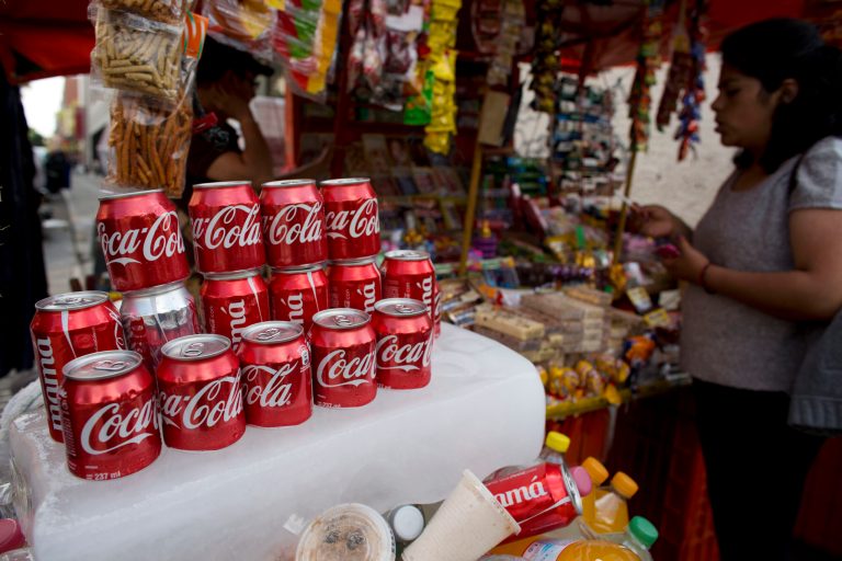 In this Oct. 9, 2014 photo, cans of Coca-Cola sit on an ice block to keep cool at a street vendor's stand in Mexico City. Coca-Cola Co. reports quarterly financial results before the market opens Tuesday, Oct. 21, 2014. (AP Photo/Rebecca Blackwell)