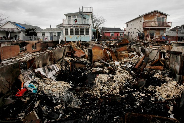   A Christmas wreath is displayed on the second floor porch railing of a home adjacent to the fire-damaged zone in the Breezy Point section of New York, Friday, Dec. 7, 2012. Over 100 homes were burned to the ground during Superstorm Sandy. (AP Photo/Mark Lennihan)  