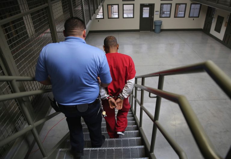 A guard escorts an immigrant detainee from his 'segregation cell' back into the general population at the Adelanto Detention Facility on Nov. 15, 2013 in Adelanto, Calif. (Photo by John Moore/Getty Images)