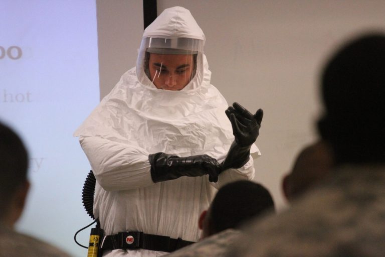 Cpl. Zachary Wicker shows how to put gloves on while in germ-protective gear in Fort Bliss, Texas, Tuesday, October 14, 2014. About 500 Fort Bliss soldiers are preparing for deployment to West Africa where they will provide support in a military effort to contain the Ebola outbreak. (AP Photo/Juan Carlos Llorca)