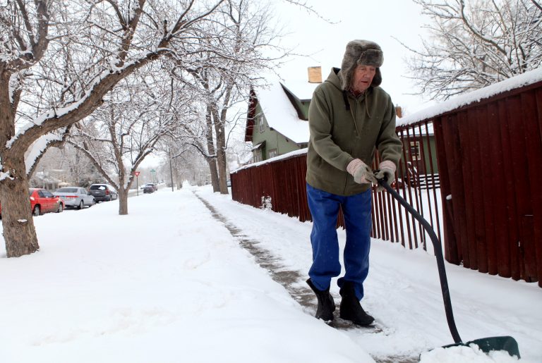 Dean Johnson clears snow from his sidewalk on Eleventh Street in Rapid City, S.D., Wednesday, April 17, 2013 after another April storm brought more snow to the area. (AP Photo/Rapid City Journal, Chris Huber)