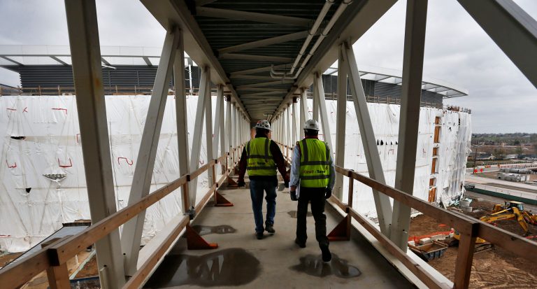Construction managers accompany members of the media during a tour of the new Veterans Administration hospital complex, which is under construction, in Aurora, Colo., just east of downtown Denver, Saturday April 18, 2015. Plumbers, electricians and drywall installers are still at work on the budget-busting Denver veterans hospital, even as the Veterans Affairs Department tries to coax another $830 million from Congress to finish the project, officials said Saturday. (AP Photo/Brennan Linsley)