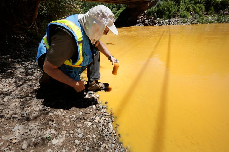 Dan Bender, with the La Plata County Sheriff's Office, takes a water sample from the Animas River near Durango, Colo., Thursday, Aug. 6, 2015. (Jerry McBride/The Durango Herald via AP)Â 