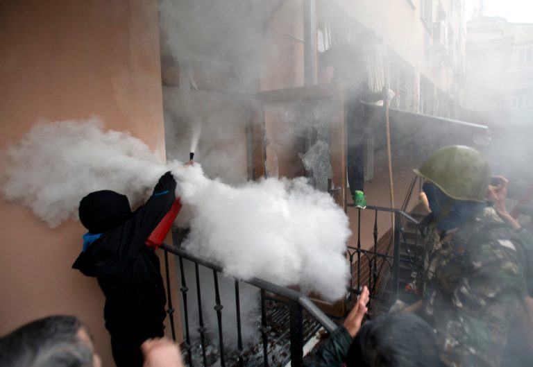A pro-Russian protester fires a fire extinguisher at riot police inside at a police station building in Odessa, Ukraine, Sunday. (AP Photo/Vadim Ghirda)