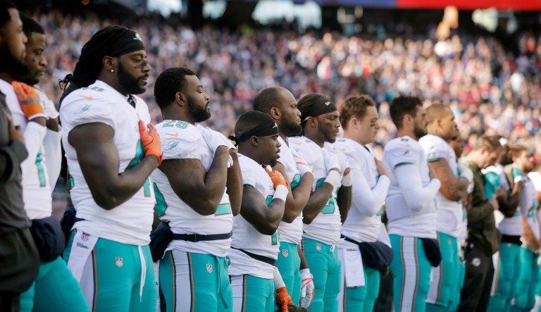Members of the Miami Dolphins team stand during the national anthem before a game in Foxborough, Mass. (AP Photo/Steven Senne)