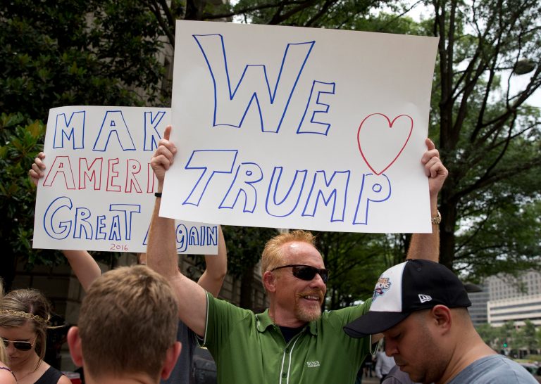 Supporters of Republican presidential candidate Donald Trump hold up signs across the street from a protest against Trump and his his portrayal of Mexican immigrants as criminals outside the new Trump hotel, in Washington, Thursday, July 9, 2015. (AP Photo/Carolyn Kaster)