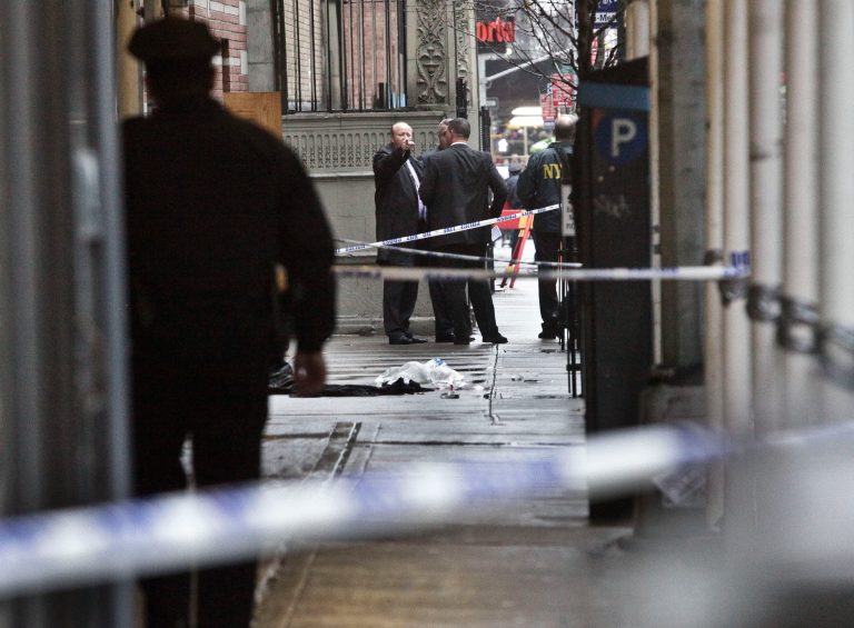   Police investigate the scene where a man was fatally shot in the back of the head in New York on Monday, Dec. 10, 2012. Authorities said the man was shot outside a school near Columbus Circle in Manhattan, lying mortally wounded in a pool of blood as the suspect escaped with a getaway driver. (AP Photo/Bebeto Matthews)  