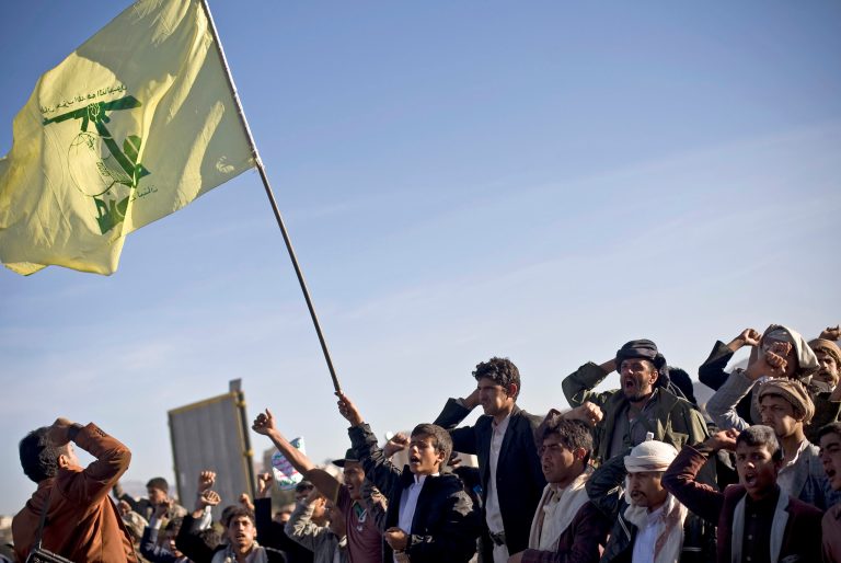 In this Wednesday, Jan. 28, 2015, file photo, a Houthi Shiite Yemeni holds a flag of Hezbollah, as others chant slogans during a rally to show support for their comrades in Sanaa, Yemen. (AP Photo/Hani Mohammed, File)