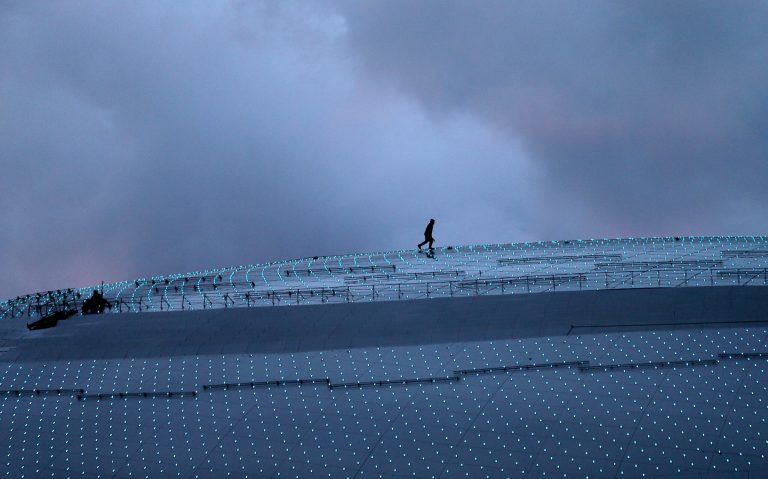 A worker walks along the roof of the Bolshoy Ice Dome at dusk while last minute preparations are underway, a day before the opening ceremony of the 2014 Winter Olympics, Thursday, Feb. 6, 2014, in Sochi, Russia. (AP Photo/Wong Maye-E)