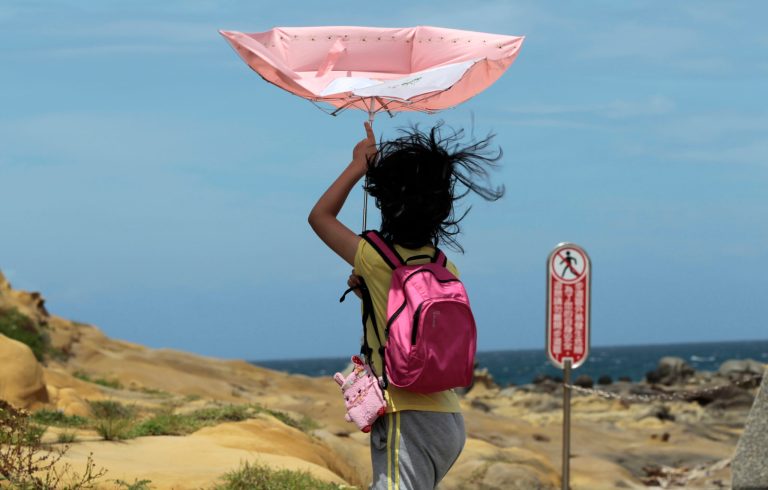 A girl struggles with winds from approaching Typhoon Matmo along the eastern coast of Keelung, northeastern Taiwan, Tuesday, July 22, 2014. The eye of Typhoon Matmo is expected to make landfall in eastern Taiwan early Wednesday bringing heavy rain and winds with gusts over 130 kilometers (85 miles) per hour. (AP Photo/Wally Santana)