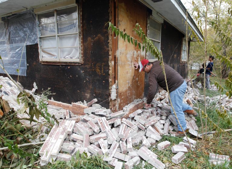 FILE - In this Nov, 6, 2011 file photo, Chad Devereaux examines bricks that fell from three sides of his in-laws home in Sparks, Okla., following two earthquakes that hit the area in less than 24 hours. A study published Thursday, July 3, 2014 by the journal Science explains how just four wells forcing massive amounts of drilling wastewater into the ground are probably causing quakes in Oklahoma. The wells seem to have triggered more than 100 small-to-medium earthquakes in the past five years, according to a study. (AP Photo/Sue Ogrocki, File)