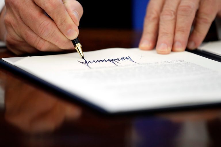 President Donald Trump signs an executive action in the Oval Office, Saturday, Jan. 28, 2017 in Washington. (AP Photo/Alex Brandon)