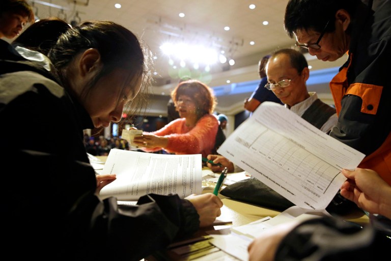 Christina Hung, left, 23, of Oakland, fills out an application form during a healthcare enrollment event at the Oakland Asian Cultural Center in Oakland, Calif. (AP Photo/Eric Risberg, File)