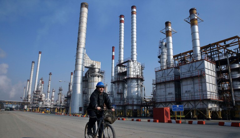 In this 2014 photo, an Iranian oil worker rides his bicycle at the Tehran oil refinery, south of the capital Tehran, Iran. A report from the the Islamic Republic News Agency mentions that President Hassan Rouhani's administration 