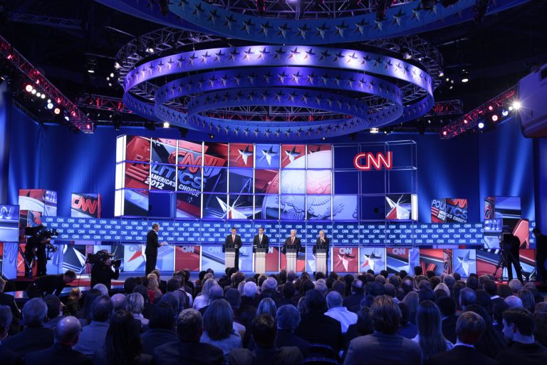 Moderator John King of CNN, left, stands on stage with Republican presidential candidates during the debate in 2012. (AP Photo/David Goldman)