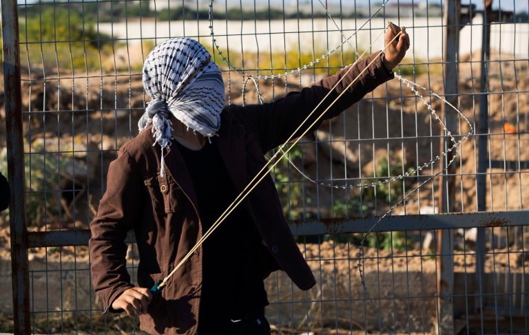 A Palestinian protester shoots a slingshot to hurl a stone during clashes with Israeli soldiers securing the entrance of the Erez border crossing between the Gaza Strip and Israel, in the northern Gaza Strip.Â The Palestinian struggle for legitimacy has been embodied in one phrase: intifada.Â (AP Photo/Adel Hana)