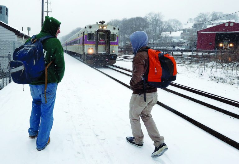 Two travelers walk to catch the last train into Boston from the Andover, Massachusetts, train station as snow falls.