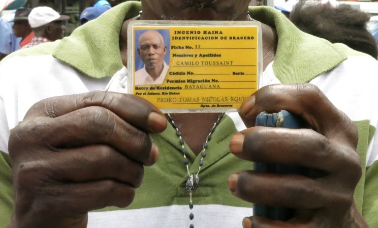 Former sugar cane worker Camilo Toussaint shows his identification card from the company he worked for during a sit-in outside Haiti's embassy in Santo Domingo, Dominican Republic, Wednesday, Sept. 17, 2014. (AP Photo/Ezequiel Abiu Lopez)