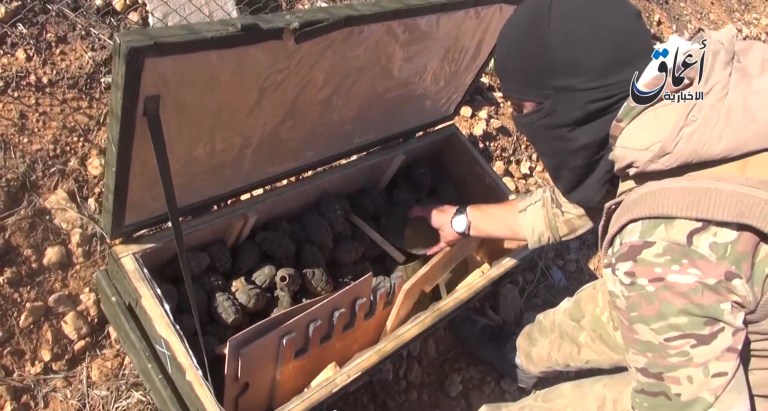This frame grab from undated video uploaded by militants shows an Islamic State group militant looking through some items from a seized cache of weapons airdropped by U.S.-led coalition forces. The weapons were meant to supply Kurdish militiamen battling the extremist group in the Syrian town of Kobani, near the border with Turkey, activists said Tuesday, Oct. 21, 2014. The video appeared authentic and corresponded to The Associated Press' reporting of the event. (AP Photo)