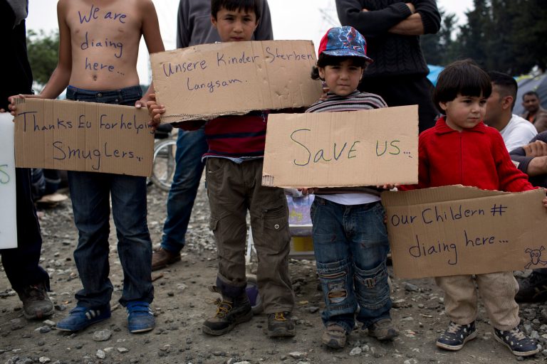 Children hold placards as migrants and refugees take part in a peaceful protest at a makeshift refugee camp of the northern Greek border point of Idomeni, Greece. The U.N. said the flow of refugees to Europe is 