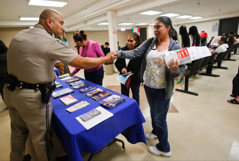In this April 23, 2014, file photo, California Highway Patrol officer Armando Garcia greets several women who were part of approximately 80 adults attending a information session regarding obtaining a California drivers license at the Mexican Consulate in San Diego.(AP Photo/Lenny Ignelzi, File)
