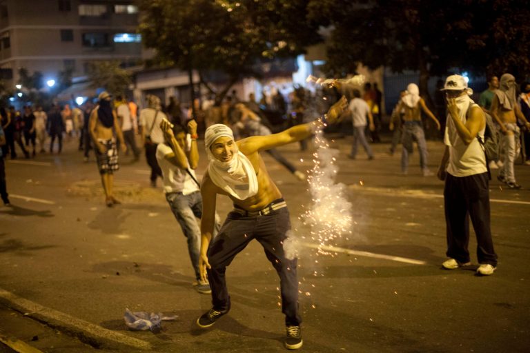 Demonstrators confront the National Guard as they protest against the official results of last Sunday's presidential elections in downtown Caracas, Venezuela, Monday, April 15, 2013. National Guard troops fired tear gas and plastic bullets to disperse demonstrators protesting the official results in Venezuela's disputed presidential election.(AP Photo/Ramon Espinosa)
