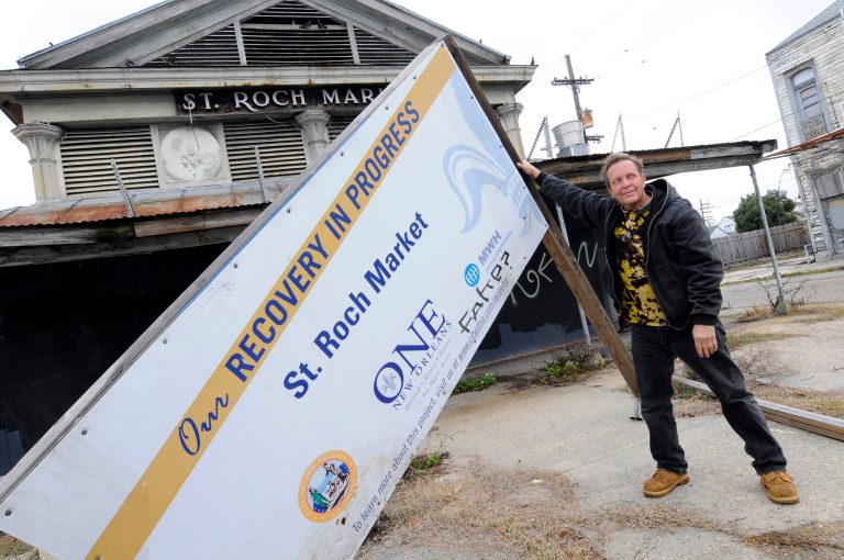 John Victorson, owner of St. Roch Tavern, holds up the fallen recovery sign in front of the dilapidated market near his business that has not been repaired since Hurricane Katrina, New Orleans, Friday, Feb. 4, 2010. (AP Photo/Cheryl Gerber)