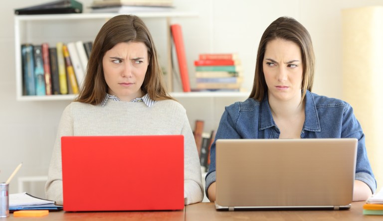 Front view portrait of two angry students studying looking each other with hate.