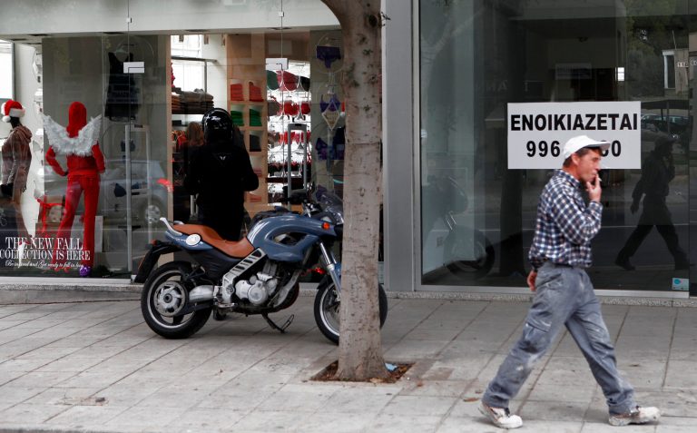   A man smokes a cigarette as he passes in front of a sign advertising a retail location for rent as another man parks his motorcycle outside a clothing shop at central Nicosia, Monday, Dec. 17, 2012. Cyprusâ state coffers are depleted and government workers may go unpaid this month unless state-owned companies urgently lend the government some â¬250 million ($329 million) from their pension funds, the finance ministryâs top civil servant warned Monday. (AP Photo / Petros Karadjias)  