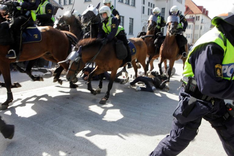Police mounted on horses ride through counter-demonstrators protesting against an election meeting arranged by the neo-nazi party 