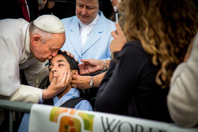 In this photo provided by World Meeting of Families, Pope Francis kisses and blesses Michael Keating, 10, of Elverson, Pa after arriving in Philadelphia and exiting his car when he saw the boy, Saturday, Sept. 26, 2015, at Philadelphia International Airport. Keating has cerebral palsy and is the son of Chuck Keating, director of the Bishop Shanahan High School band that performed at Pope Francis' airport arrival. (Joseph Gidjunis/World Meeting of Families via AP)