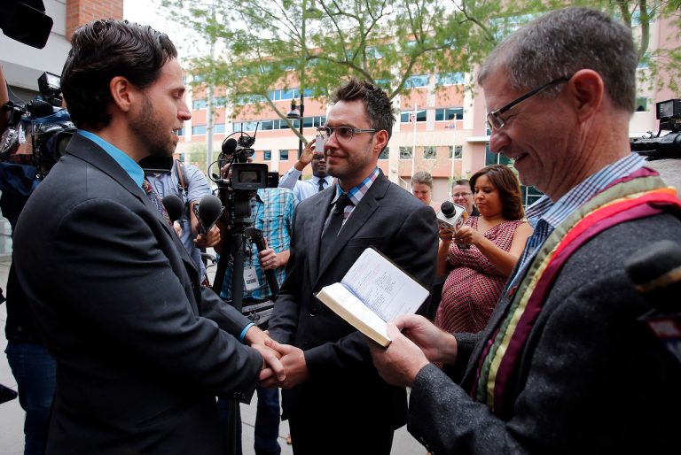 Kevin Patterson, left, and David Larance exchange vows as Rev. John Dorhaer, right, officiates the ceremony Friday in Phoenix. (AP/Rick Scuteri)