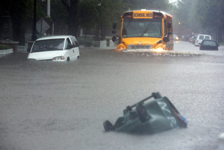 A school bus tries to go through a flooded Bagnall Road in Norfolk, Va., on Monday, Sept. 8, 2014 while a stalled vehicle sit on the side and a trash bin is floats down the street during a heavy rain. Gov. Terry McAuliffe will address the new Climate Change and Resiliency Commission on Wednesday, Sept. 10, when its 30-plus members meet in Richmond. (AP Photo/The Virginian-Pilot, The' N. Pham)