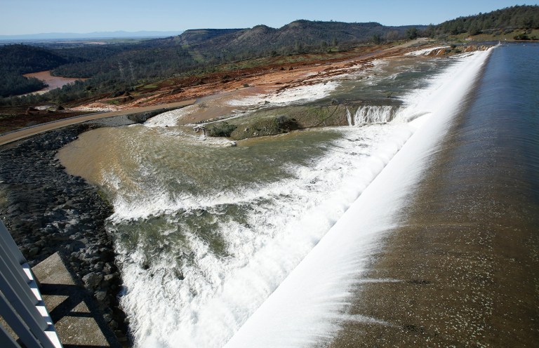 Water flows over the emergency spillway at Oroville Dam in Oroville, Calif. Water started flowing over the emergency spillway at the nation's tallest dam for the first time Saturday after erosion damaged the Northern California dam's main spillway. (AP Photo/Rich Pedroncelli)