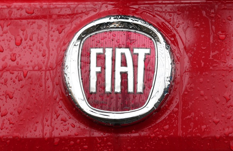 FILE - In this Thursday, Jan. 2, 2014 file photo, rain falls on a Fiat logo pictured on a car  in Milan, Italy. Italian carmaker Fiat SpA, which controls Chrysler, says its second-quarter profits dropped by more than a half due to lower performance in North and Latin America. Fiat said Wednesday, July 30, 2014, that net profit was 197 million euros ($263 million), compared with 435 million euros in the same period last year. North American volumes were up 10 percent, driven by incentives to dealers to sell legacy Chrysler vehicles, but the incentives also cut into profits. Earnings before interest and tax in the region dropped 18 percent to 598 million euros. In Latin America, revenues dropped 13 percent as vehicle shipments fell 21 percent. Fiat said revenues in the quarter rose to 23.3 billion euros, up 1 billion euros over the same quarter last year. Fiat is currently finalizing its merger with Chrysler. (AP Photo/Antonio Calanni, File)