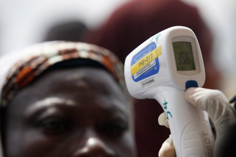 A Nigerian port official uses a thermometer to screen Muslim pilgrims for Ebola at the Hajj camp before boarding a plane for Saudi Arabia at the Murtala Muhammed International Airport in Lagos, Nigeria, last week. ( AP Photo/Sunday Alamba)