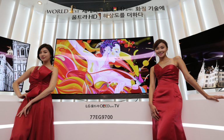 Models pose with LG Electronics' 77-inch Ultra organic light-emitting diode (OLED) TV during a press unveiling in Seoul, South Korea, Monday, Aug. 25, 2014. LG Electronics Inc. is sticking with its strategy of using the exceptionally expensive OLED display technology for TVs, announcing two new giant models with ultra-high definition screens. (AP Photo/Ahn Young-joon)