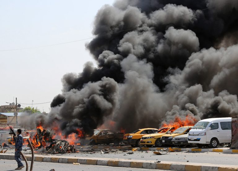 FILE - In this file photo taken Tuesday, May 13, 2014, an Iraqi policeman stands by burning vehicles moments after one in a series of bombs hit the Shiite stronghold of Sadr City in Baghdad, Iraq. Violence has claimed the lives of 799 Iraqis in May, the highest monthly death toll so far this year, the United Nations said on Sunday, June 1, underlining the daunting challenges the government faces as it struggles to contain a surge in sectarian violence. (AP Photo/Karim Kadim, File)