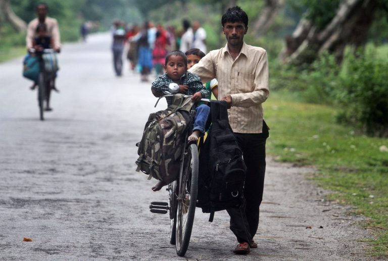 A villager pushes a bicycle carrying children and belongings, leaving their violence-affected village of Narayanguri, in the northeastern Indian state of Assam, Saturday, May 3 2014. Police in India arrested 22 people after separatist rebels went on a rampage, burning homes and killing dozens of Muslims in the worst outbreak of ethnic violence in the remote northeastern region in two years, officials said Saturday. (AP Photo/Anupam Nath)